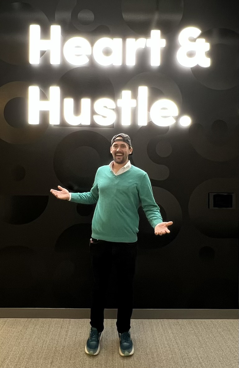 Tommy Smith smiling beneath a Heart & Hustle sign